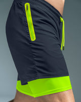 Pantaloneta deportiva con bolsillo lateral con bóxer interno#color_536-azul-oscuro-verde-neon